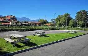 Zona de aparcamiento con mesas de picnic y espacio ajardinado