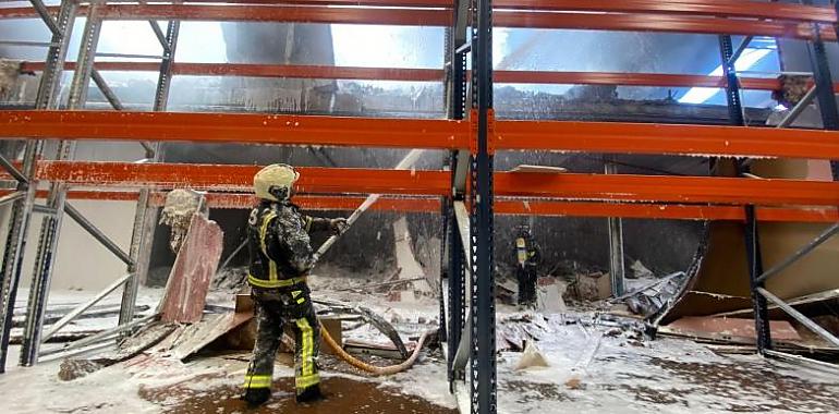 A esta hora aún continúan los trabajos de los servicios de emergencia en el incendio declarado esta mañana en una zona industrial de Siero
