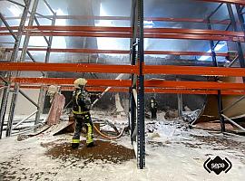 A esta hora aún continúan los trabajos de los servicios de emergencia en el incendio declarado esta mañana en una zona industrial de Siero